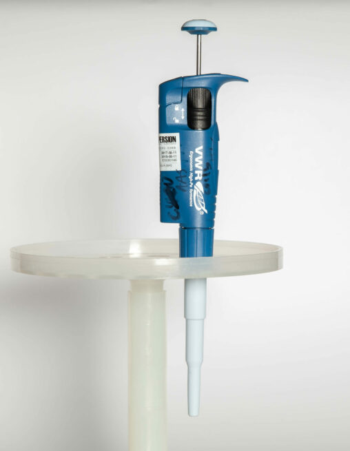 An electronic variable volume pipette held in a plastic stand.