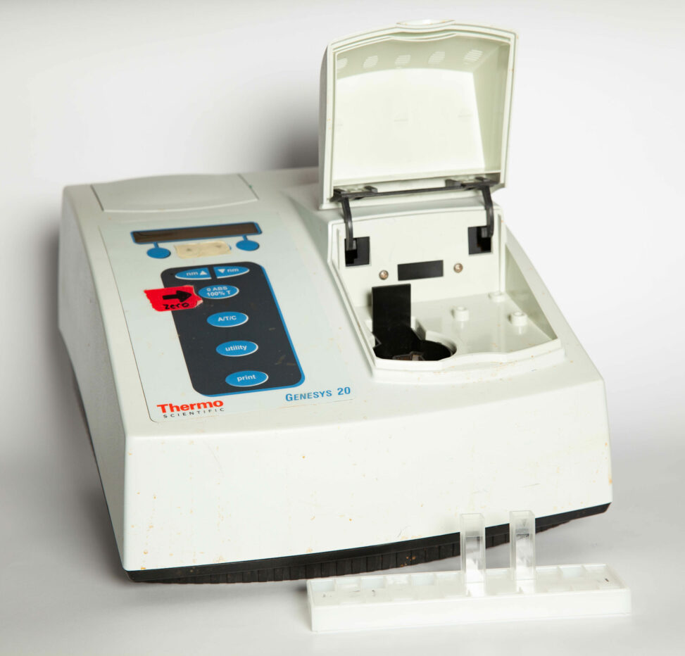 An opened spectrometer with two plastic cells in a rack in front of it.