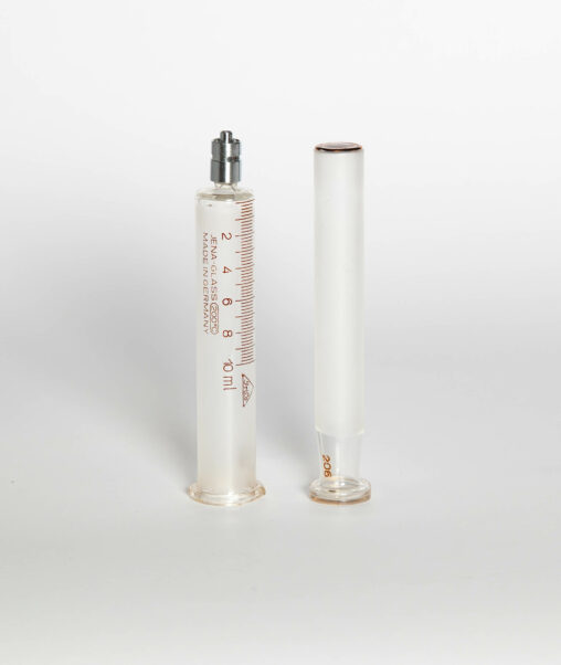 Two pieces of a Luer lock glass syringe.