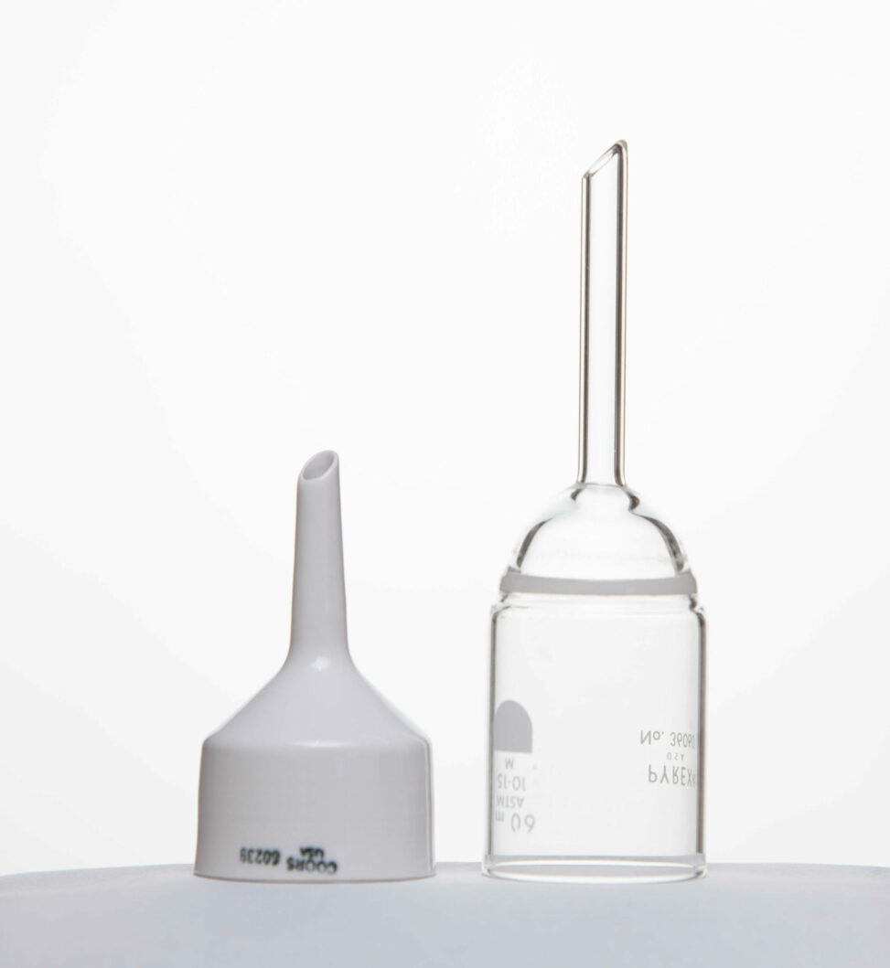 A porcelain Buchner funnel beside a glass Buchner funnel with a sintered Borosilicate glass frit.