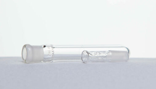 A 2 ml glass test tube and its stopper lay horizontally side by side.