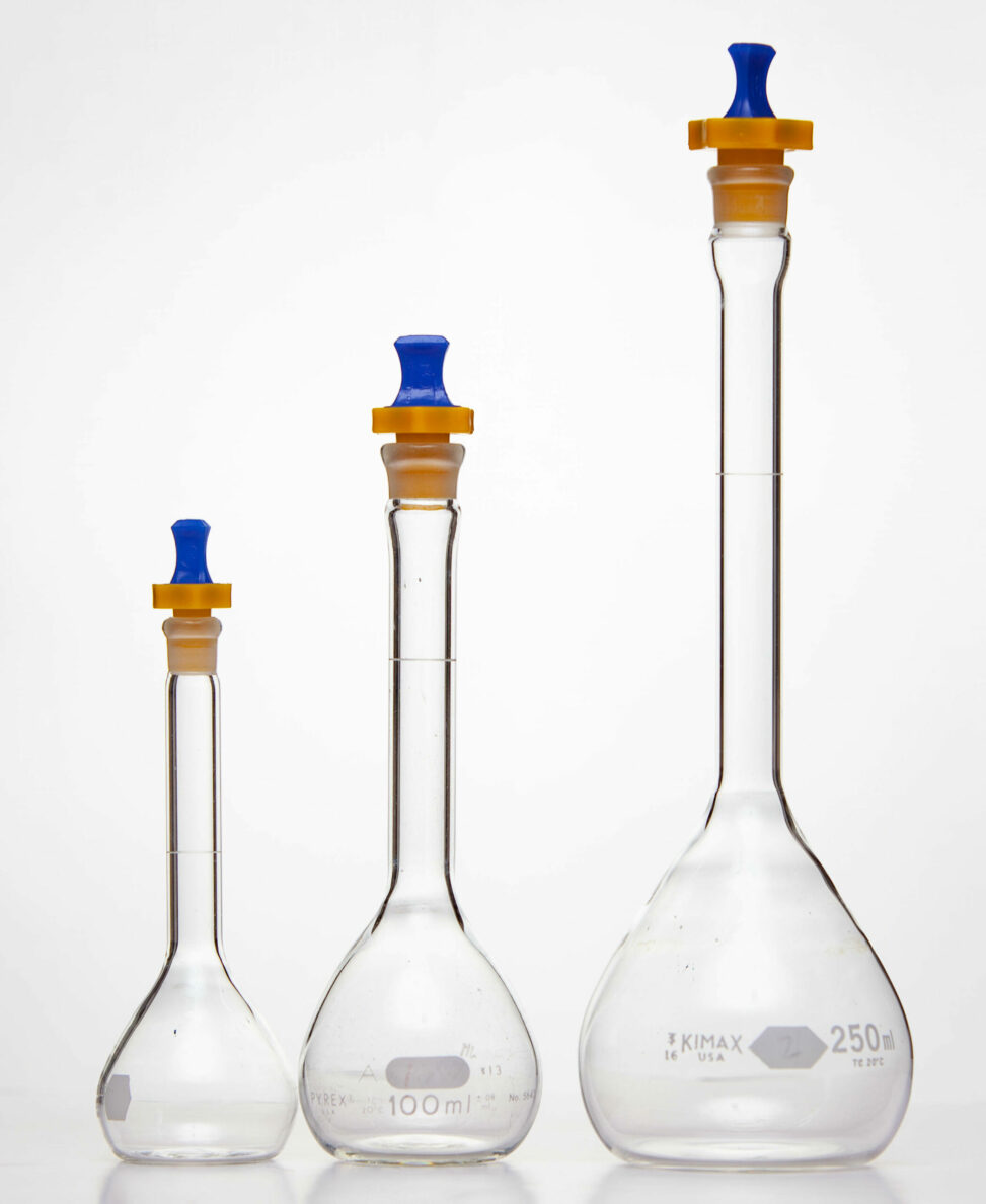 Three different sizes of volumetric flasks with blue and orange stoppers.