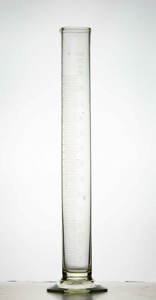 A glass graduated cylinder with a flat bottom.